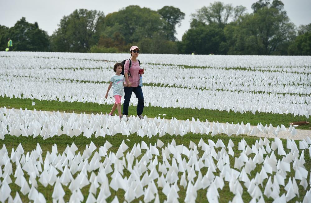 A woman and child walk through the art exhibit on the National Mall honoring COVID-19 victims on Thursday.