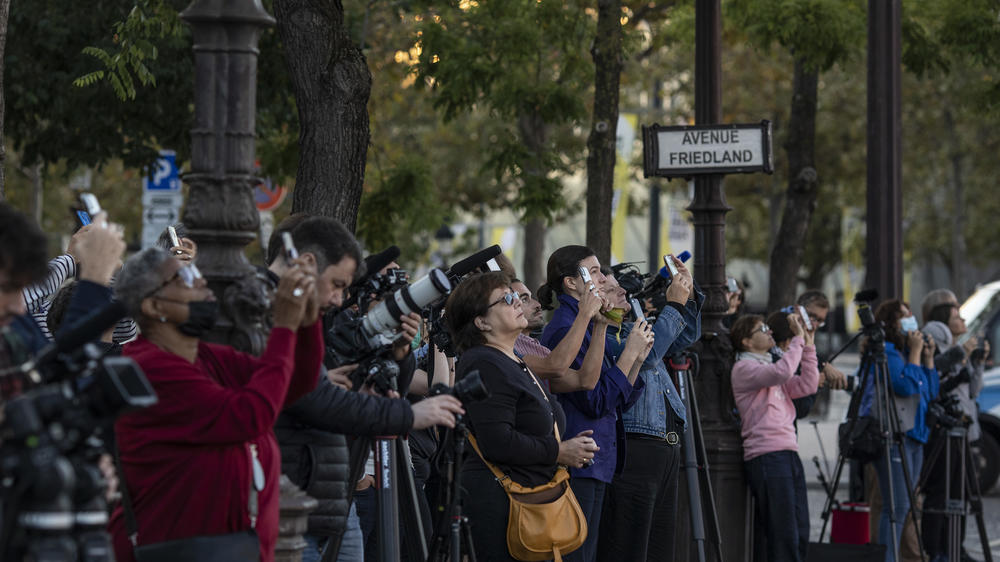 Spectators and journalists watch as workers start the process of wrapping the Arc De Triomphe monument in Paris on Sept. 12.
