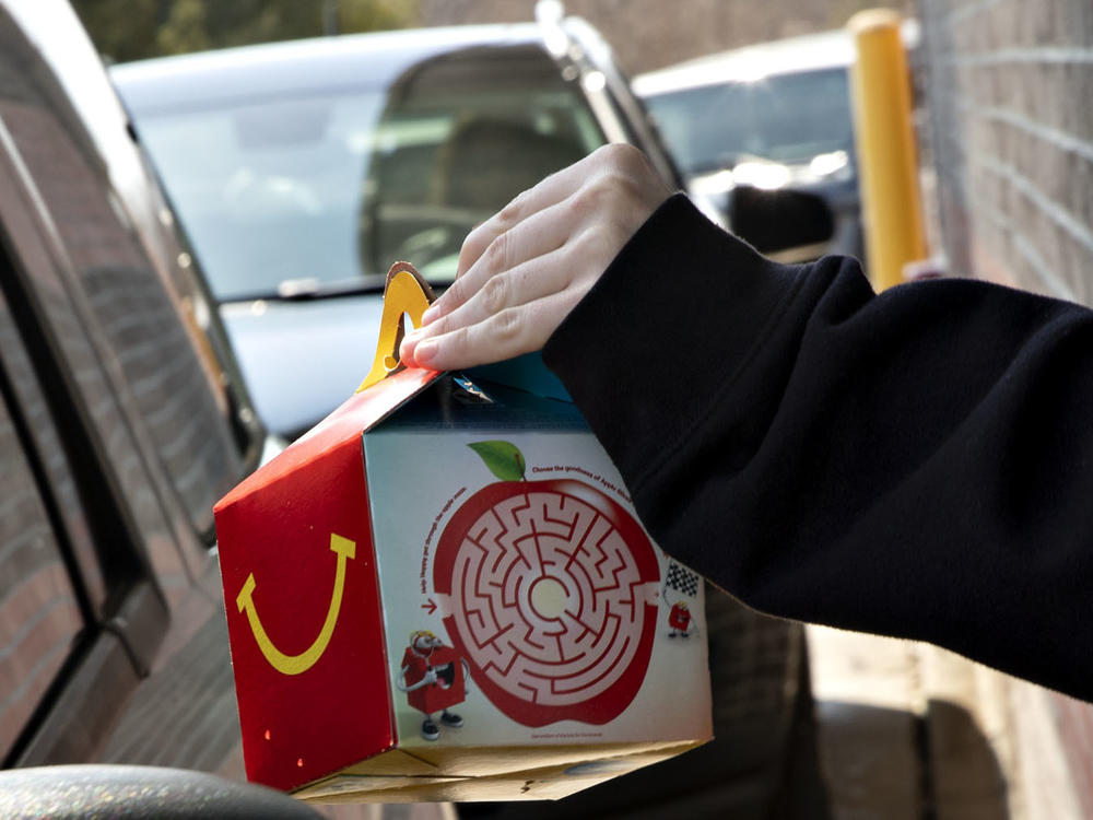 McDonald's says it will phase out most plastic from its Happy Meals by 2025. Here, a customer picks up a kid's meal at a McDonald's drive-through.