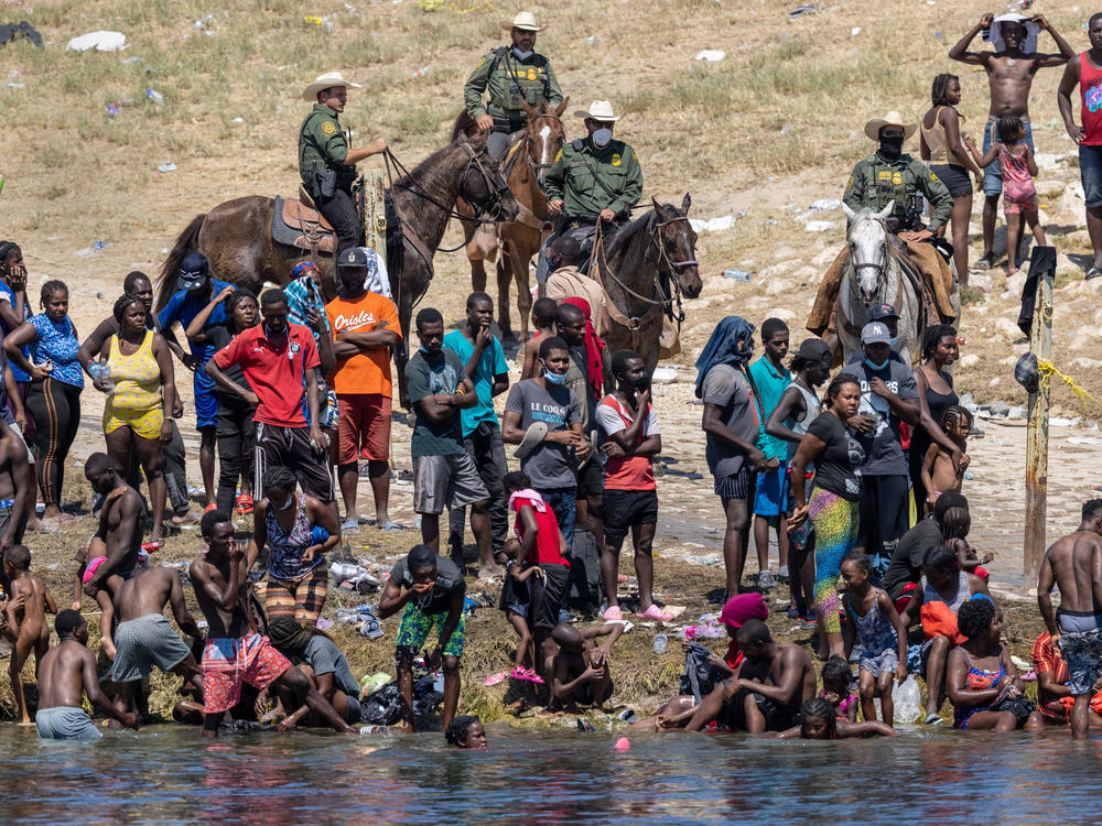 Mounted Border Patrol agents watch Haitian migrants Monday on the banks of the Rio Grande in Del Rio, as seen from Ciudad Acuña, Mexico.