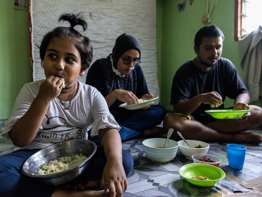 Mohd Ali, right, of Selangor, Malaysia, lost his job due to the pandemic. The family's favorite foods — fried chicken, eggs, fruit and bread — are now typically out of reach. When they can afford chicken, they give most of it to their daughter, Hosna.