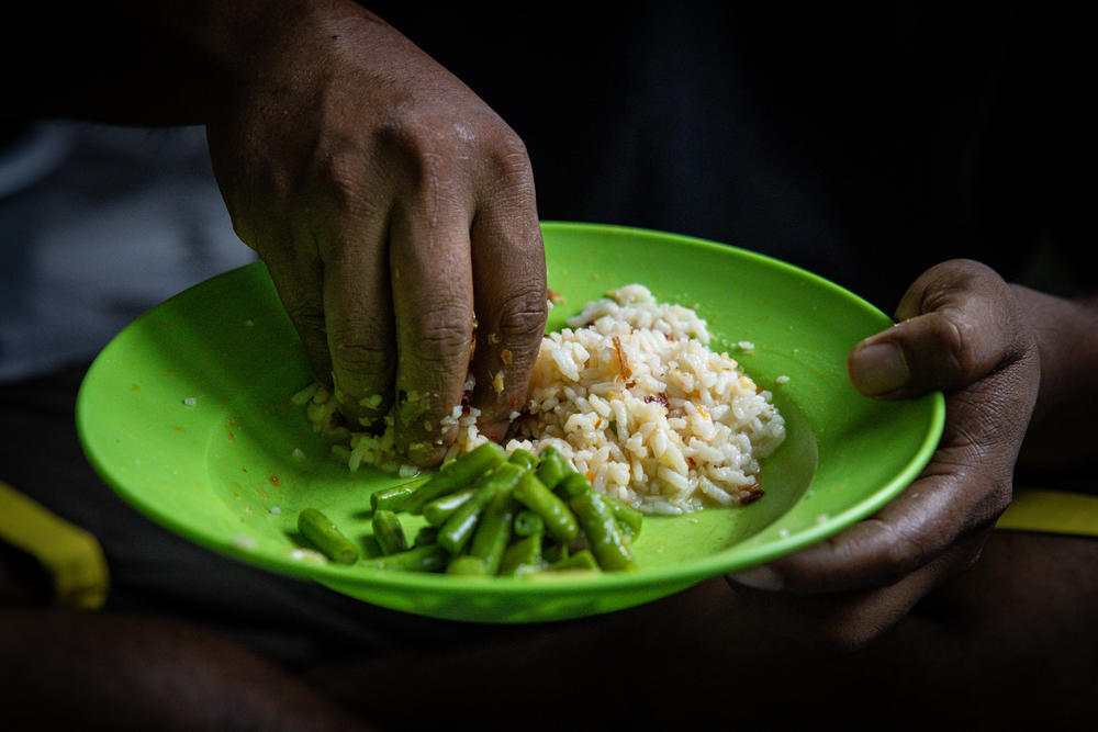 Ali eats a typical Malaysian dish of long beans and rice.