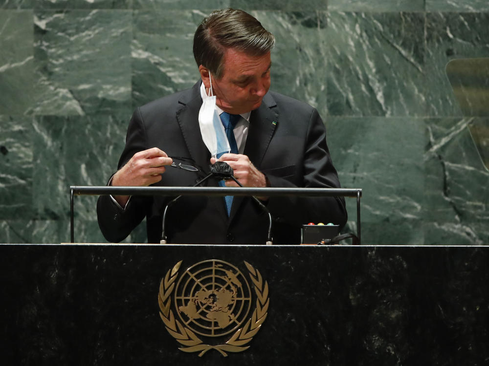 Brazil's President Jair Bolsonaro pulls off his protective face mask to address the 76th Session of the U.N. General Assembly at United Nations headquarters in New York, Tuesday, Sept. 21, 2021.