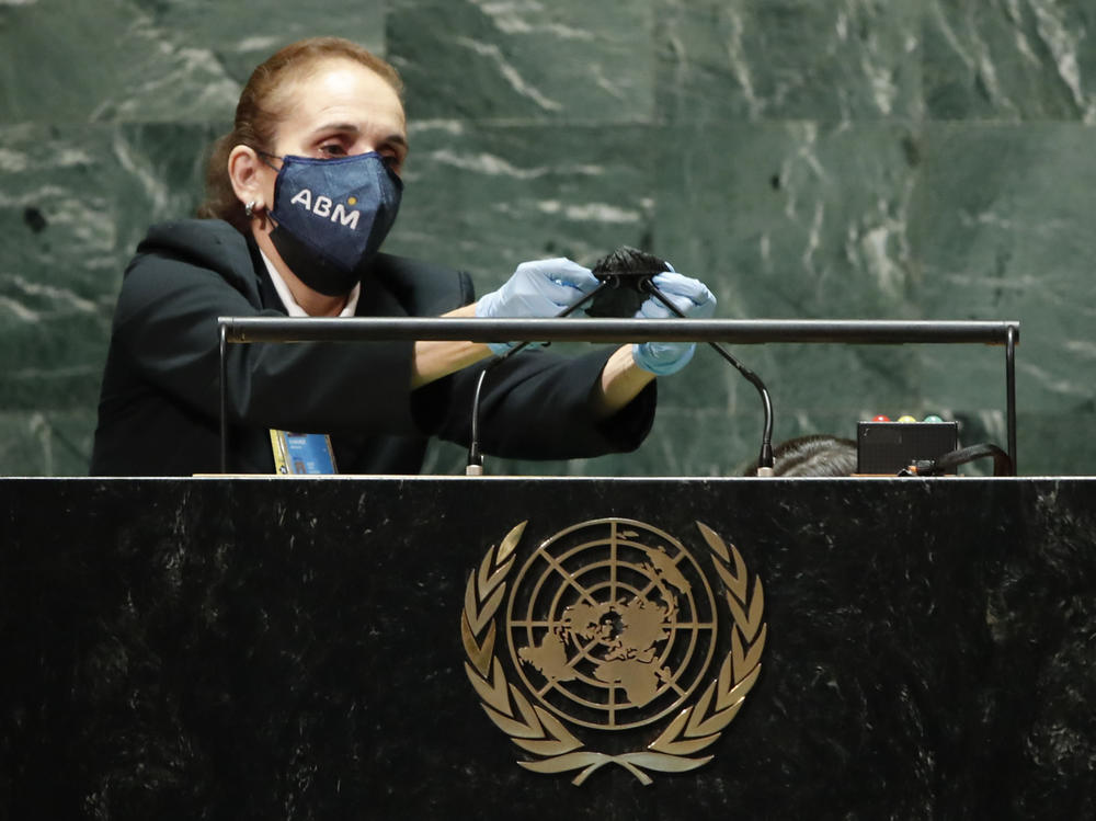 A United Nations employee cleans the microphones at the podium after Brazil's President Jair Bolsonaro spoke and before the start of President Joe Biden's address during the 76th Session of the U.N. General Assembly, Tuesday, Sept. 21, 2021, at United Nations headquarters in New York.