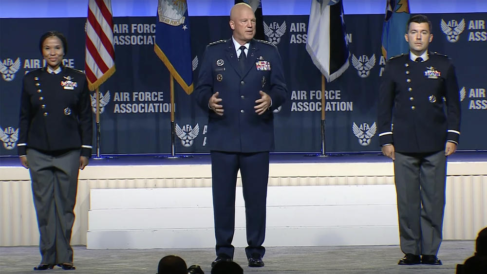 The chief of space operations, Gen. John Raymond, stands between two Space Force guardians as the branch unveils prototypes for its new service dress uniforms.