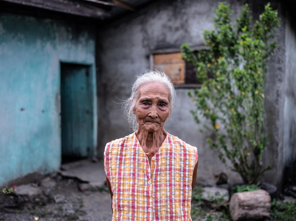 Gloria Hernandez, 82, stands outside her home in Aliaga, a village in the Philippines, where she lives with her daughter and grandsons. During the pandemic, she has been struggling to afford fresh meat and fish.