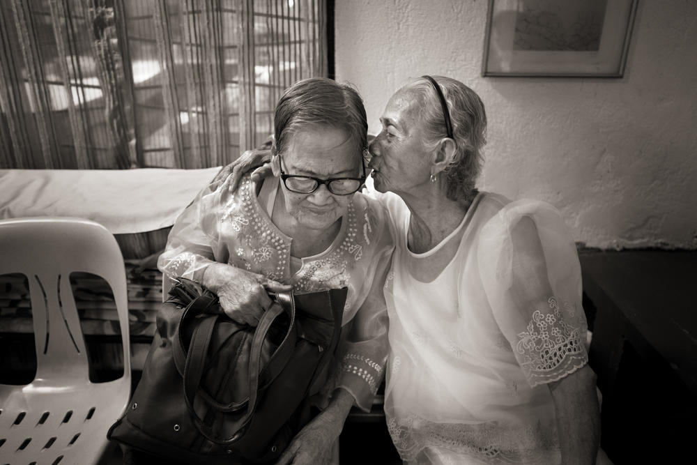 Narcisa Claveria, right, whispers in Estelita Dy's ear as a group of 