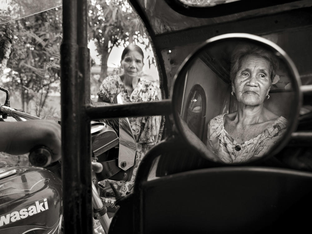 Isabelita Vinuya, 88, reflected in mirror, bids farewell to Perla Bulaon Balingit in the village of Mapaniqui in Pampanga. They are two of the last living 