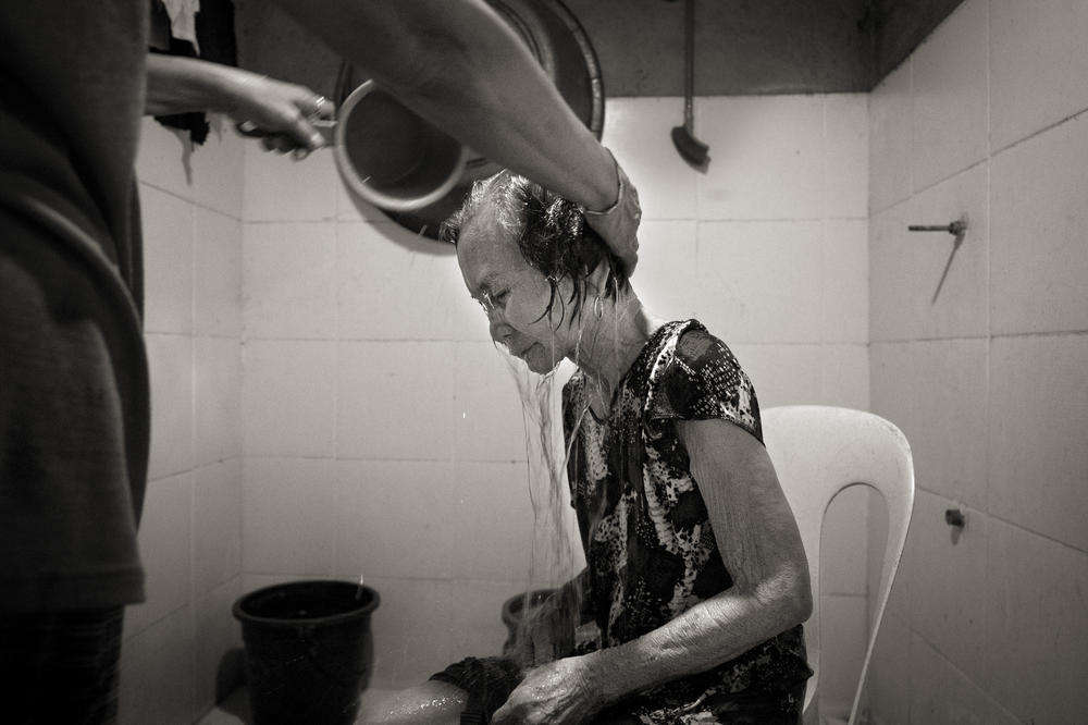 Ailing and infirm, Januaria Galang Garcia is bathed by a family member in the village of Mapaniqui in Pampanga, Philippines, on May 19, 2019. Garcia died on Sept. 3, 2021.  She was 9 when Japanese soldiers laid siege to her village during World War II, killing the men and raping the women and girls.