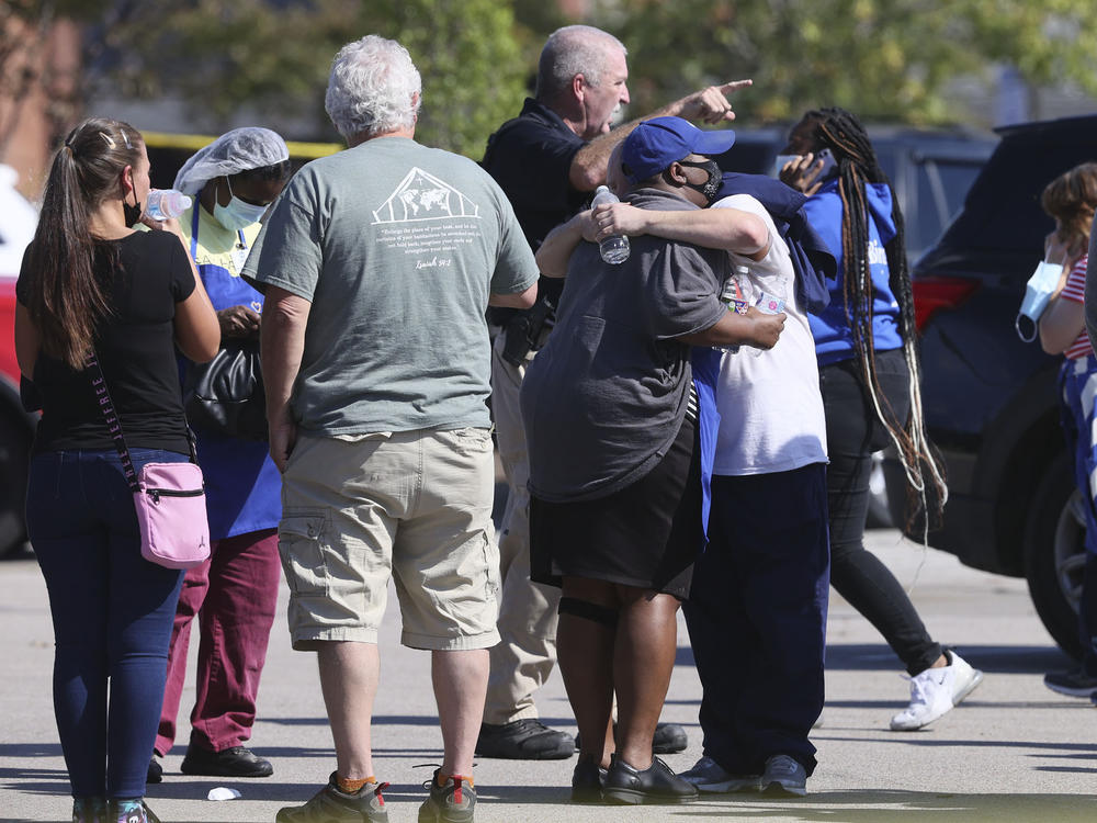 People embrace as police respond to the scene of a shooting at a Kroger grocery store in Collierville, Tenn., on Thursday. Police say 13 people were injured, one of whom has died. The suspected shooter also died from what police say was a self-inflicted gunshot wound.