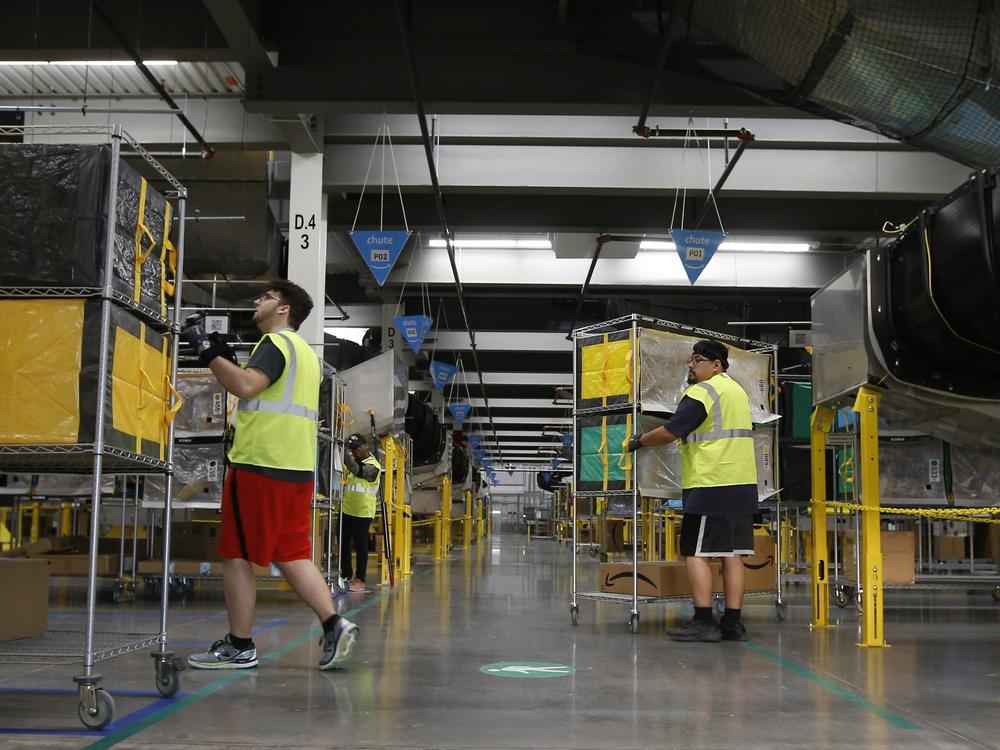 Amazon workers move containers to delivery trucks at an Amazon warehouse facility in Goodyear, Ariz., in December 2019.