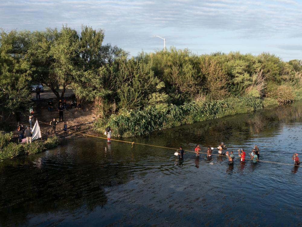 Haitian migrants cross the Rio Grande on Wednesday to get food and water in Mexico, as seen from Ciudad Acuña, Mexico. The U.S. is allowing some migrants to enter the country and sending others back to Haiti.