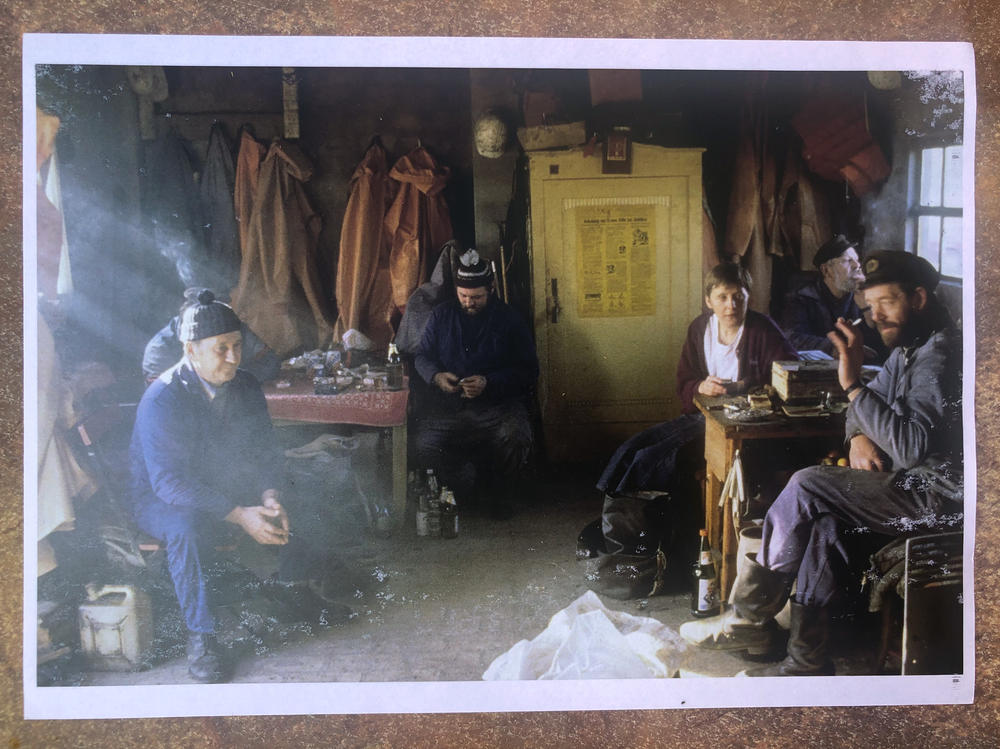 A photo of Hans-Joachim Bull's November 1990 picture with Angela Merkel, taken during Merkel's first campaign stop as a parliamentary candidate. Merkel chatted with Bull (far left, obscured behind another fisherman) and other fishermen in their hut. She asked about their concerns, and Bull and his colleagues told her they were worried about new European fishing quotas.