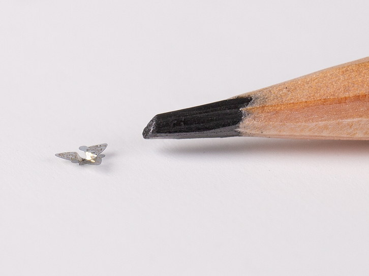 A 3D microflier next to a pencil tip for scale.