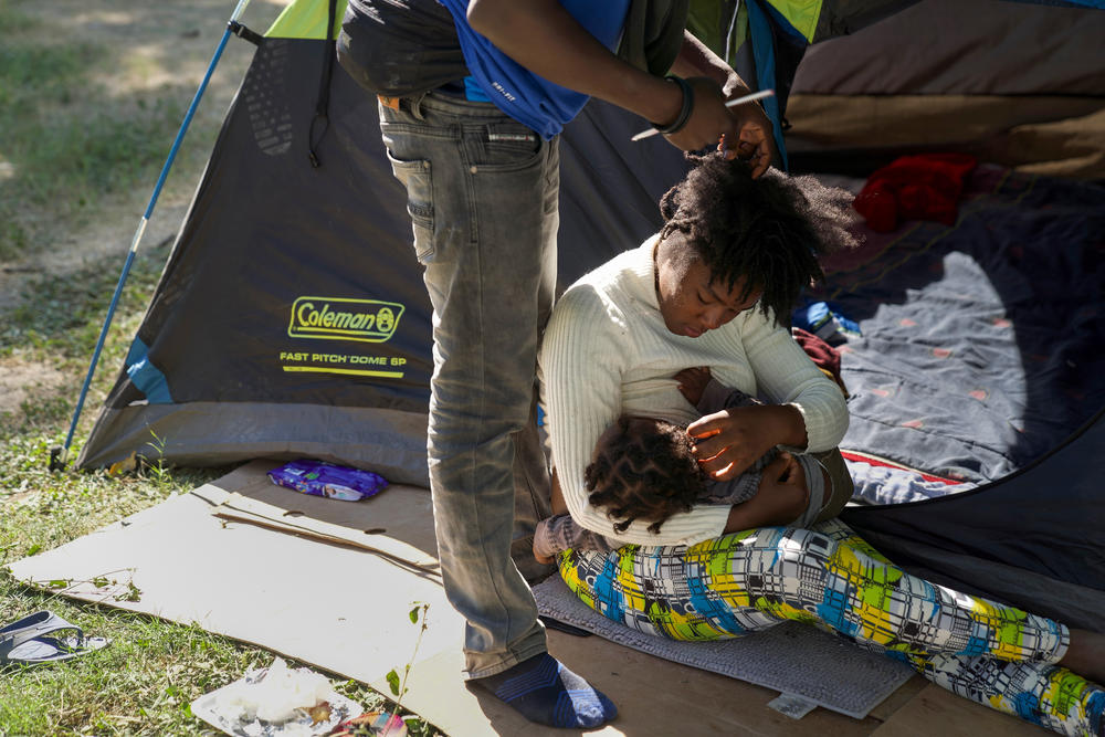 A mother feeds her baby outside their tent.