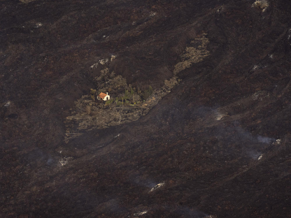 Lava from a volcanic eruption surrounds a house on the island of La Palma in the Canary Islands on Thursday.