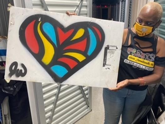 Nadine Seiler poses with a piece of artwork that was once displayed on the fence outside the White House. Seiler is working to find new homes for the 700+ signs/artifacts.