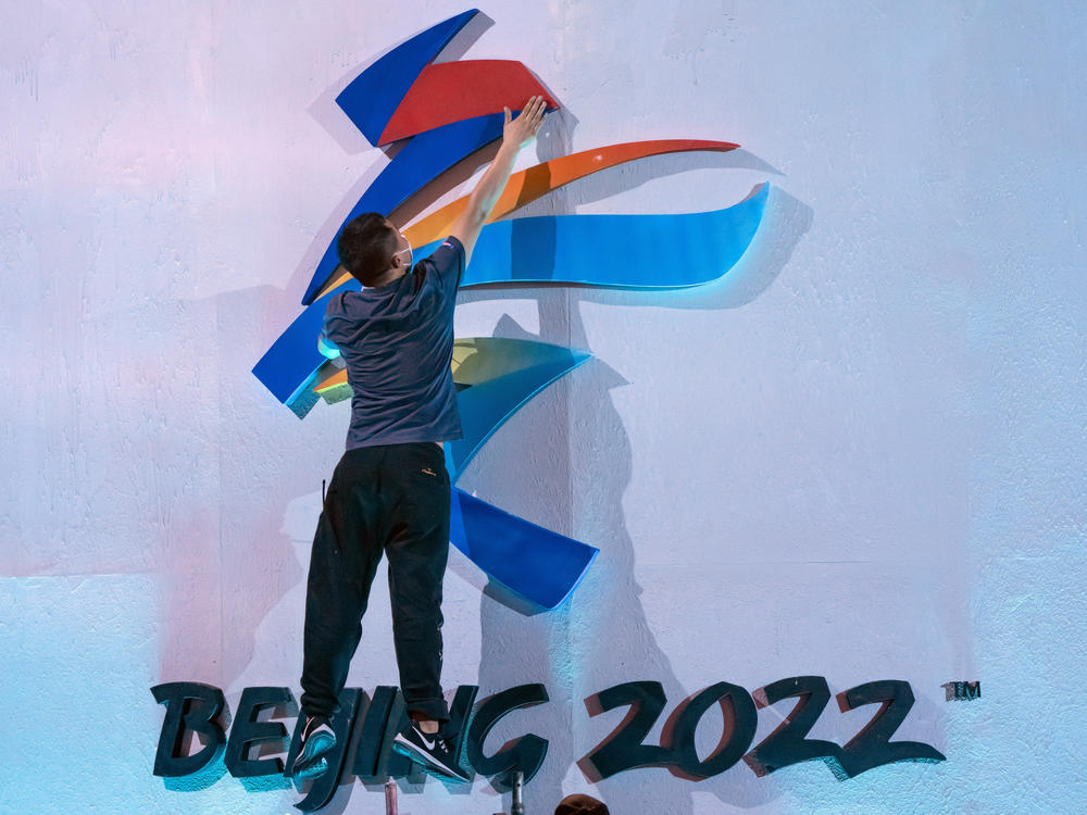 A crew member leaps to fix a logo for the 2022 Winter Olympics in Beijing earlier this month. The International Olympic Committee says it will allow fans from mainland China to attend the competition in person.