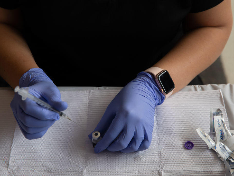 A health care worker fills syringes with doses of the COVID-19 vaccine in August in Southfield, Mich.