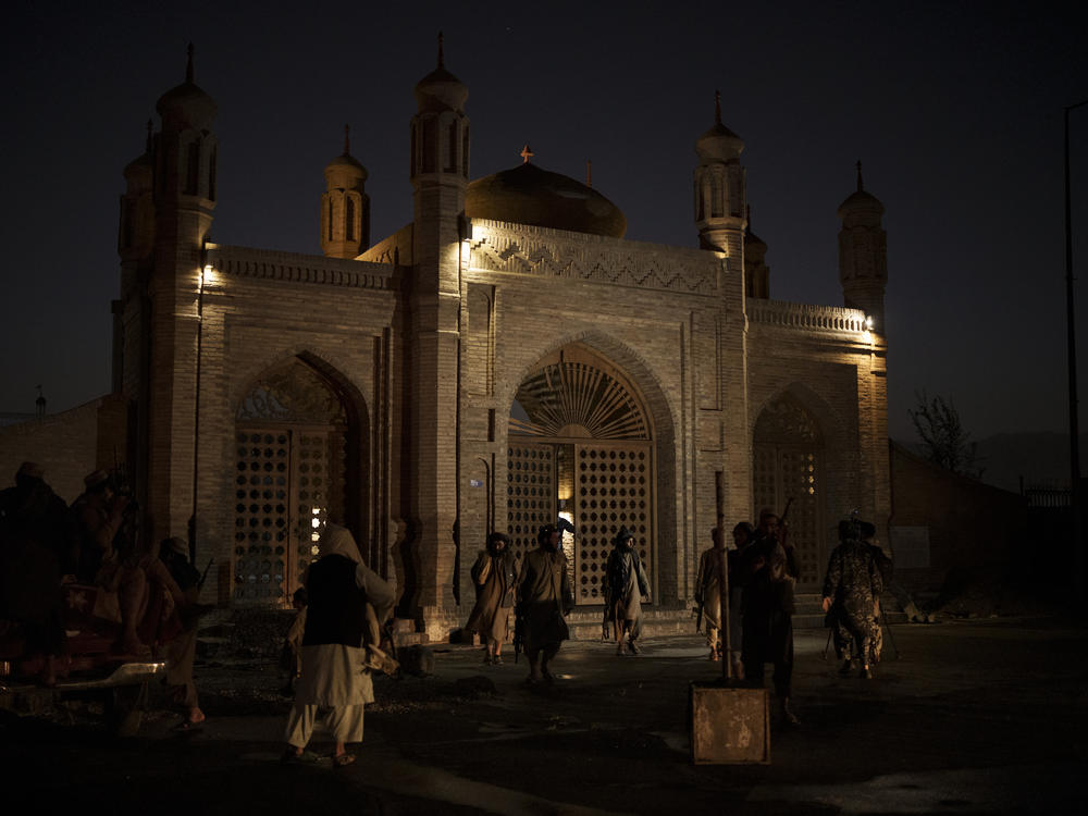 Taliban fighters walk at the entrance of the Eidgah Mosque after an explosion in Kabul, Afghanistan, Sunday, Oct. 3, 2021. The attack left a 