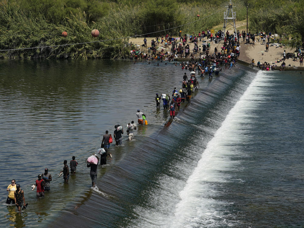 In this Sept. 18, 2021, file photo Haitian migrants use a dam to cross into the United States from Mexico in Del Rio, Texas.