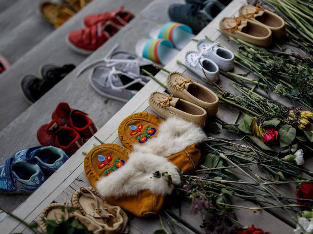 Flowers, shoes and moccasins sit on the steps of the main entrance of the former Mohawk Institute, which was a residential school for Indigenous kids, in Brantford, Ontario. The memorial is to honor the children whose remains were discovered in unmarked graves in recent months in Canada.