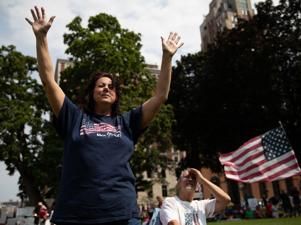 Sharon Lofquist raises her arms to religious music as demonstrators gathered to protest vaccine mandates outside the Michigan State Capitol in Lansing in August.