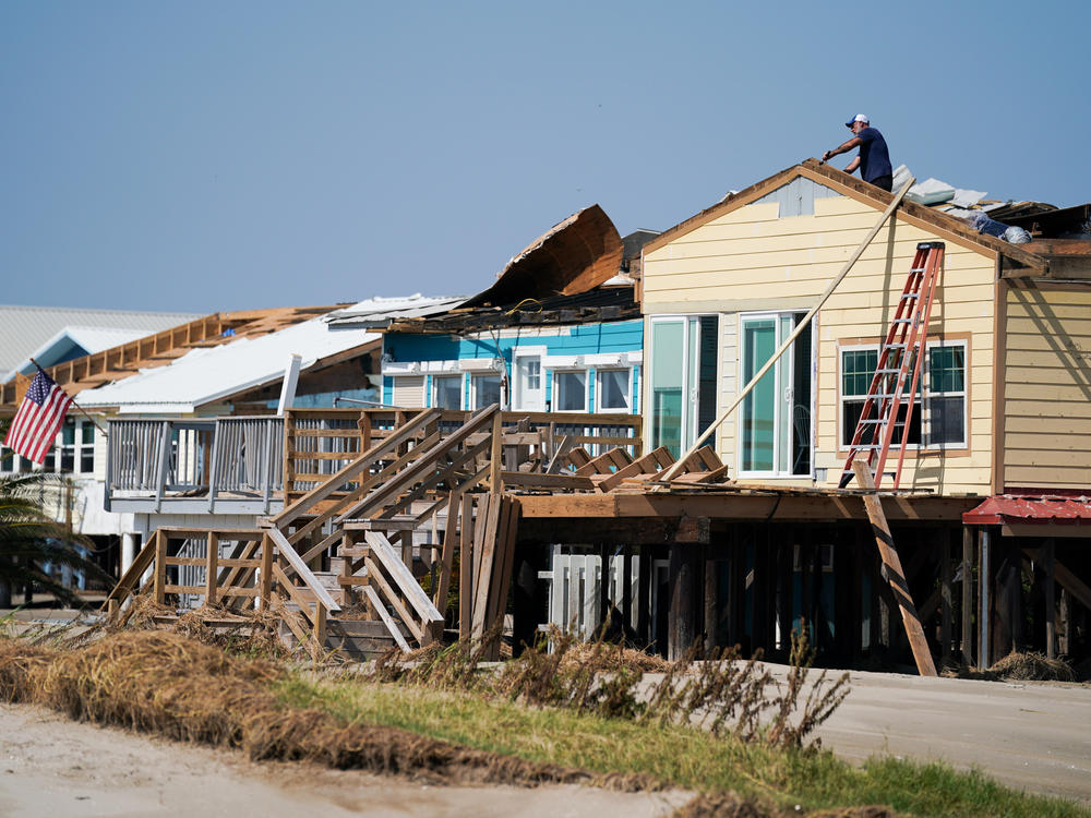 A man works on the roof of a storm-damaged house on Sept. 4 after Hurricane Ida swept through Grand Isle, La. A new poll finds that two-thirds of Americans say if their home is hit by an extreme weather event they'd rather rebuild than relocate.