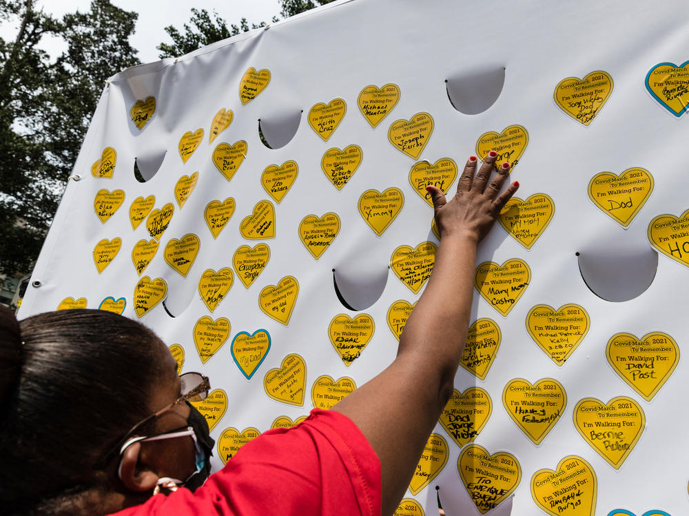 COVID-19 survivors gather in New York and place stickers representing lost relatives on a wall in remembrance of those who have died during the pandemic.