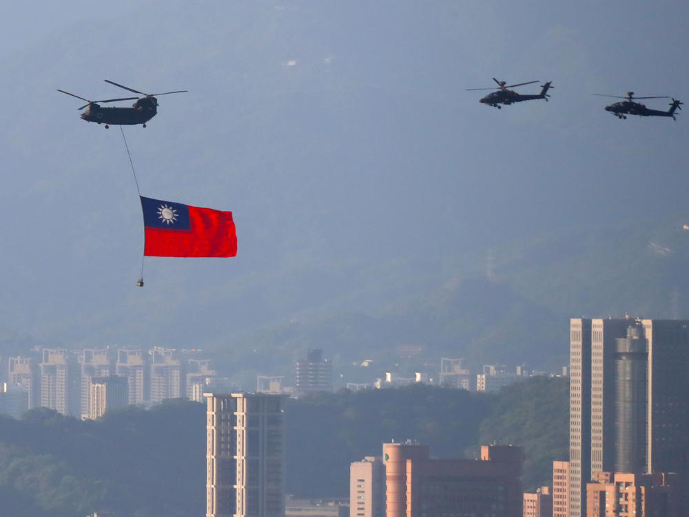 A military helicopter carrying a Taiwanese flag flies near the Taipei 101 building as part of the rehearsal ahead of the Double Ten National Day celebration in New Taipei, Taiwan, on Tuesday.