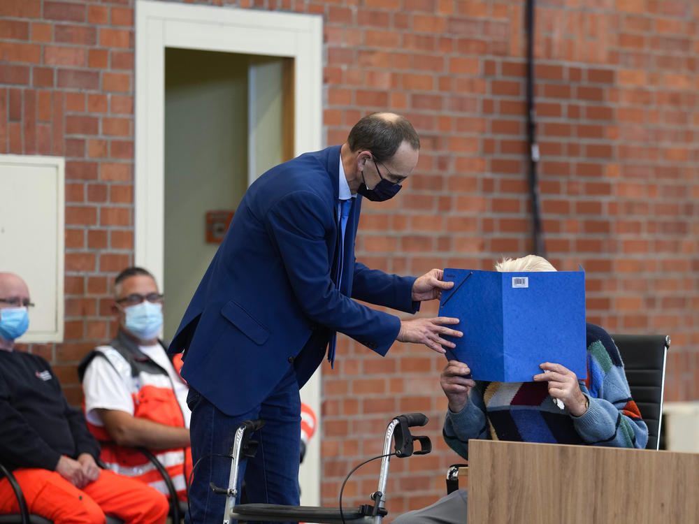 Lawyer Stefan Waterkamp covers the face of accused Josef S. at the court room in Brandenburg, Germany, on Oct. 7, 2021. The 100-year-old man is charged as an accessory to murder on allegations that he served as a guard at the Nazis' Sachsenhausen concentration camp.