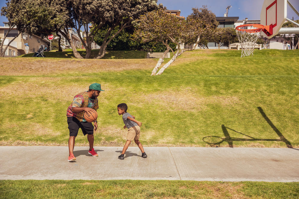 A park visitor, Dorian Hill, plays basketball with his son at Bruce's Beach. He says he felt drawn to the park before he knew the history. 