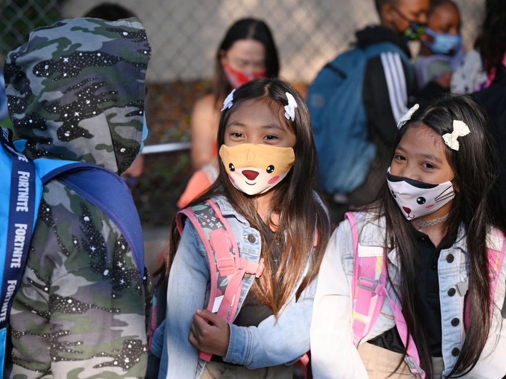 Students and parents arrive masked for the first day of the school year at Grant Elementary School in Los Angeles on Aug. 16. The reopening of schools has raised hope that some parents may return to the labor force.