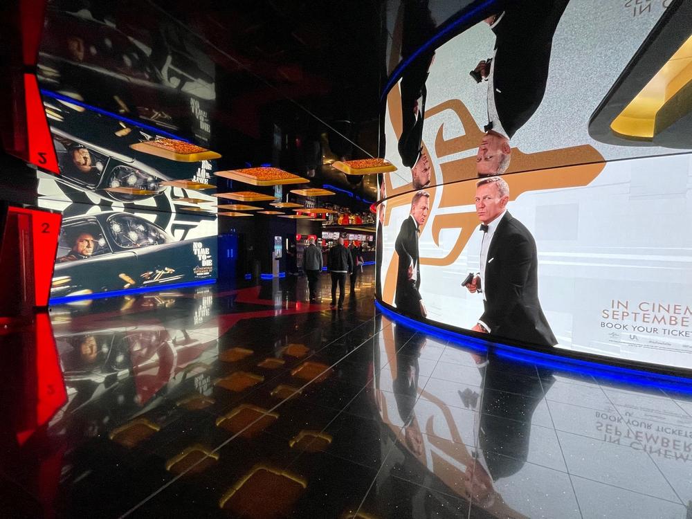 Advertisements in a theater in London's Leicester Square show Daniel Craig as James Bond in <em>No Time to Die.</em> Ahead of its opening in the U.S. this weekend, the film had taken in more than $120 million in 54 foreign markets.