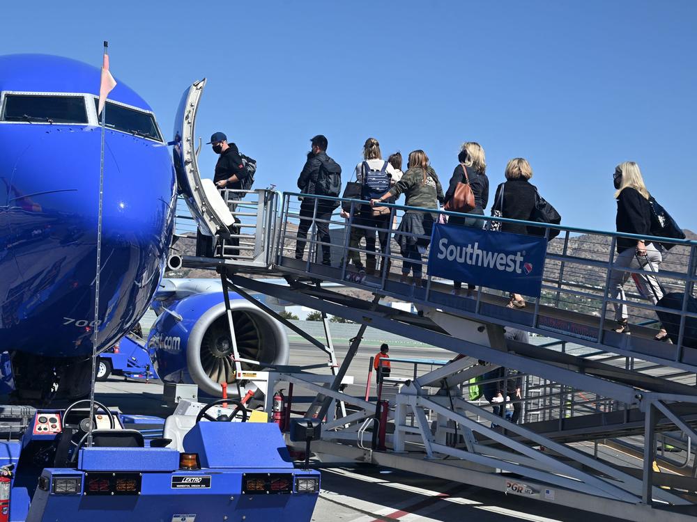 Passengers board a Southwest Airlines airplane at Hollywood Burbank Airport in Burbank, California on October 10, 2021. The airline has continued to cancel or delay hundreds of flights on Monday.