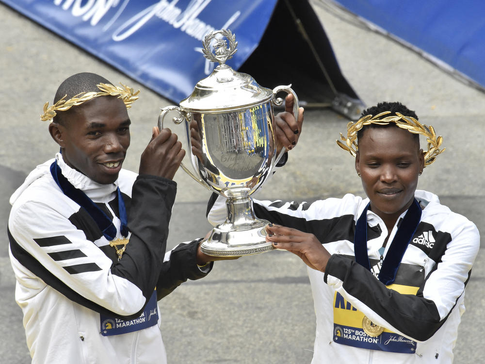 Benson Kipruto (L) and Diana Kipyogei (R) of Kenya hold up the victory trophy after taking first place in the professional men's and women's divisions during the 125th Boston Marathon in Boston, Massachusetts on Monday. The first Boston Marathon since April 2019 strayed from tradition in several ways.
