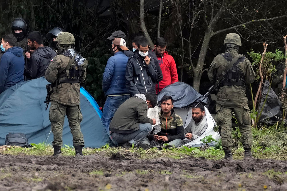 Migrants are seated, after crossing the border from Belarus into Poland in the village of Usnarz Gorny, Poland, in September. An estimated 16,000 migrants have been stopped by Poland's border patrol for illegally crossing the country's 250-mile-long border with Belarus since August.