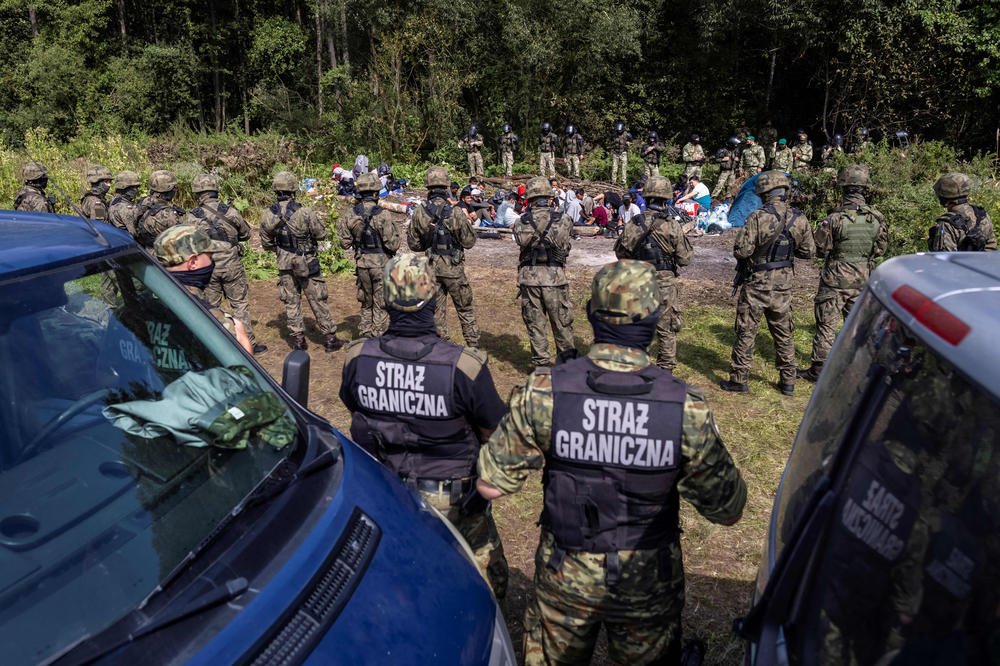 Polish border guards stand near a group of migrants believed to be from Afghanistan in the small village of Usnarz Gorny near Bialystok, northeastern Poland, located close to the border with Belarus, in August.