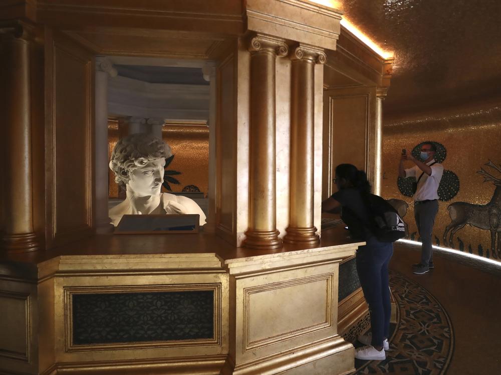In this Friday, Oct. 1, 2021 file photo, visitors take photos of the 3D re-production of Michelangelo's David at the Italy's pavilion at the Dubai Expo 2020 in Dubai, United Arab Emirates. One of the most talked about attractions at the world's fair underway in Dubai is a towering statue made of marble dust that's raising eyebrows just as its original form did more than 500 years ago.
