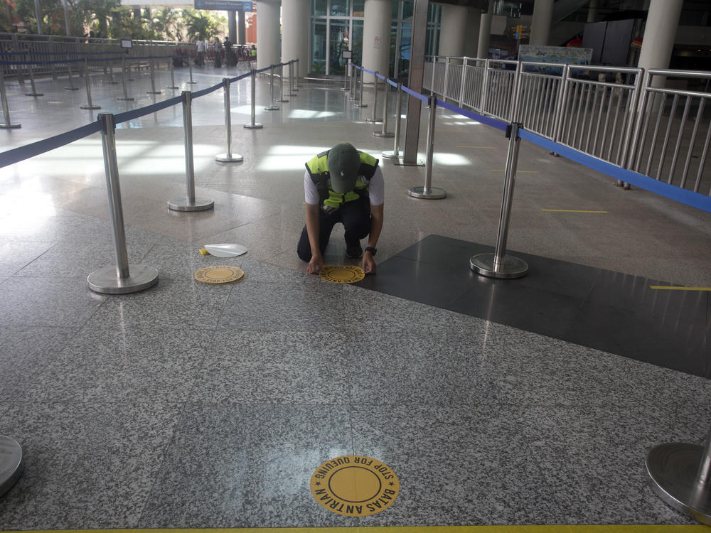 An airport worker marks queue line for the reopening of International Ngurah Rai Airport in Bali, Indonesia, Thursday.