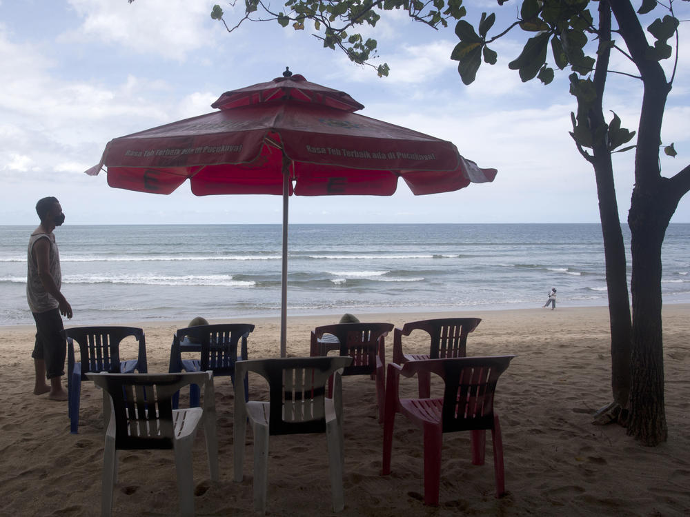 A beach vendor sets chairs as he waits for customers in Kuta beach in Bali, Indonesia, on Thursday. The Indonesian resort island of Bali welcomed international travelers to its shops and white-sand beaches for the first time in more than a year Thursday - if they're vaccinated, test negative, hail from certain countries, quarantine and heed restrictions in public.