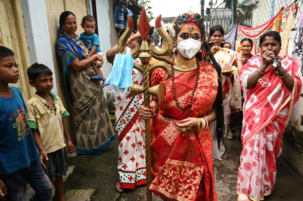 A youth dressed as the Hindu goddess Durga distributes face masks as part of a COVID-19 awareness campaign ahead of the Durga Puja festival in Kolkata on Oct. 10.