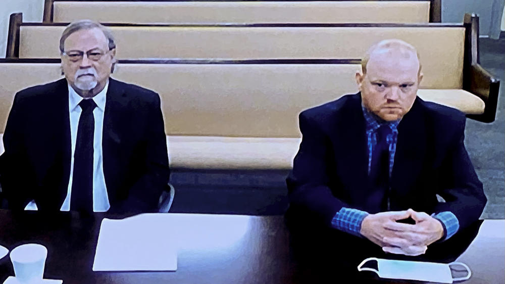 In this image made from video, from left, father and son, Gregory and Travis McMichael, accused in the shooting death of Ahmaud Arbery, listen via closed circuit TV in the Glynn County Detention center in Brunswick, Ga., on Nov. 12.