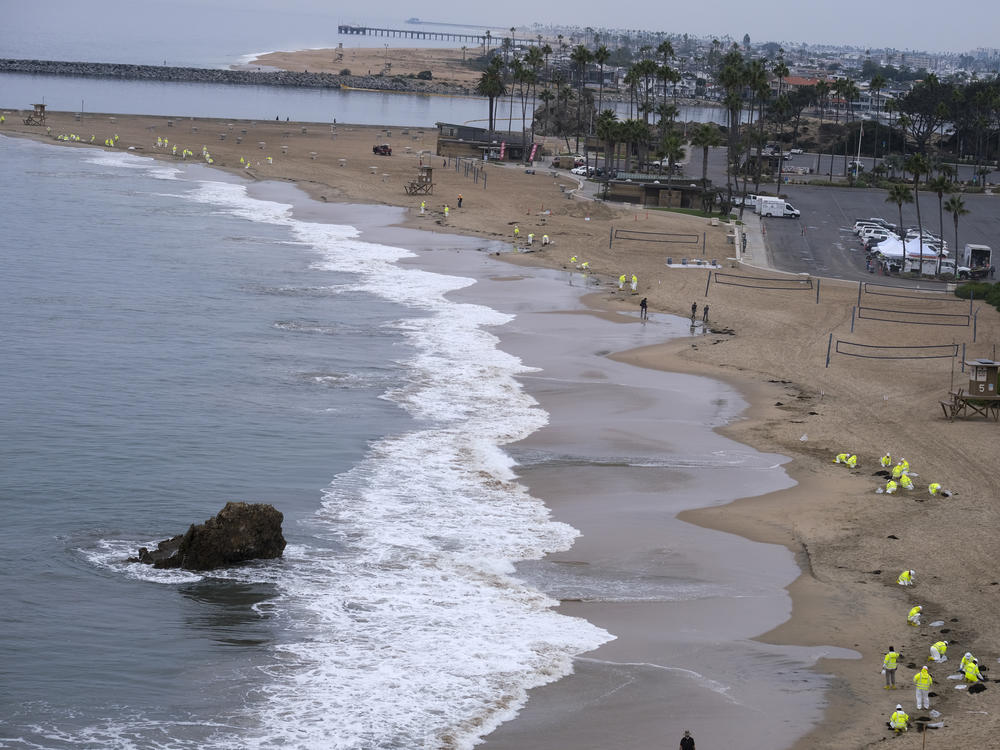 Workers in protective suits clean the contaminated beach in Corona Del Mar on Oct. 7 after an oil spill in Newport Beach, Calif.