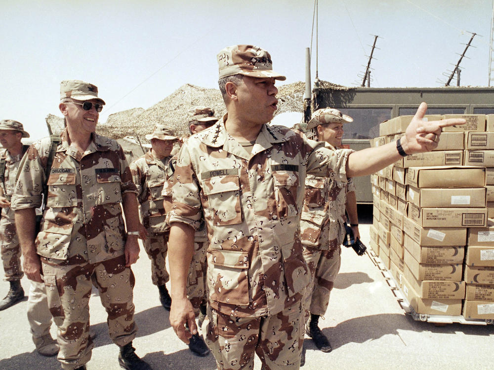 Gen. Colin Powell, chairman of the Joint Chiefs of Staff, points to a group of American troops at an airbase after his arrival in Saudi Arabia on Sept. 13, 1990. Powell served as chairman under both Presidents George H.W. Bush and Bill Clinton.