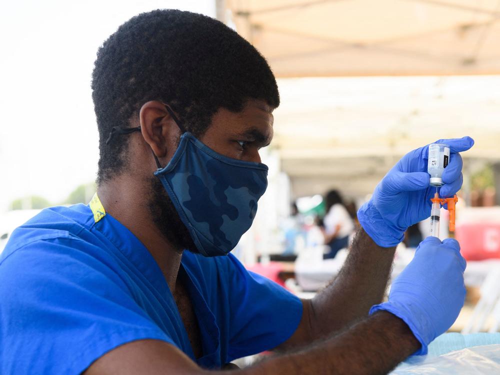 A health care worker prepares a dose of the Moderna COVID-19 vaccine during a clinic held at the Watts Juneteenth Street Fair in the Watts neighborhood of Los Angeles.