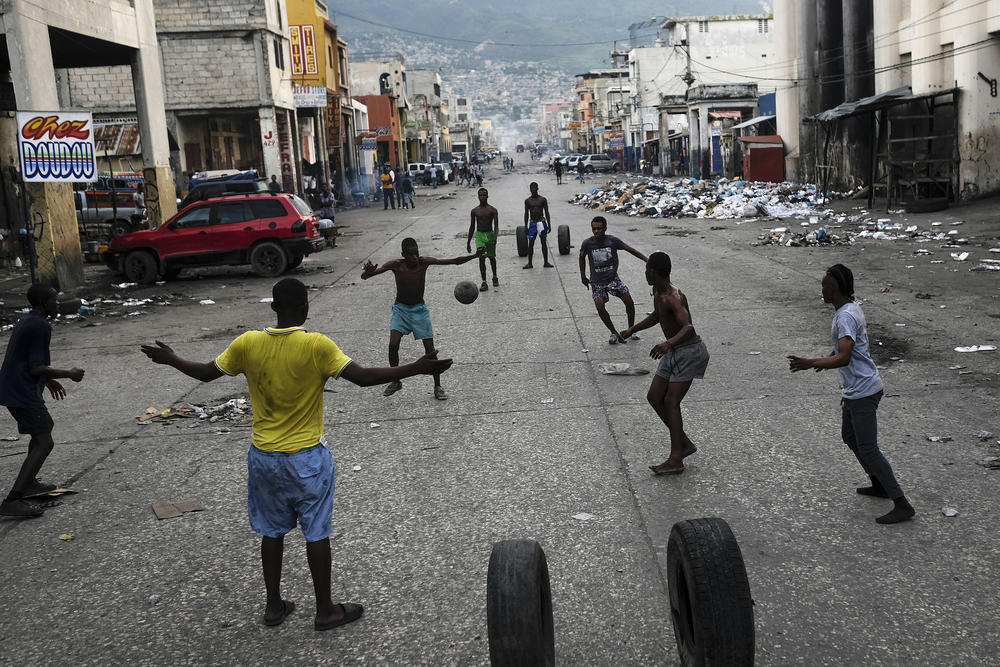Youths play soccer next to businesses that are closed due to a general strike in Port-au-Prince on Monday.
