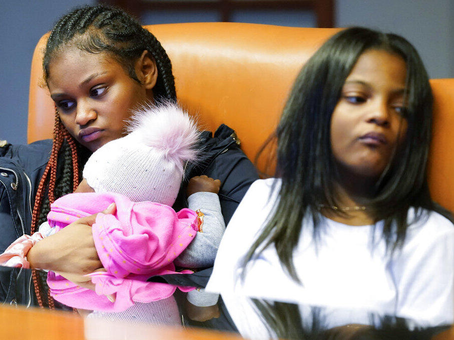 Savannah, left, holds her daughter Chanel, as she sits with her sister Telia, as they listen to their mother Krystal Archie talking Sept. 23 during an interview with the Associated Press in Chicago. Archie's three children were present when police, on two occasions 11 weeks apart, kicked open her front door and tore apart the cabinets and dressers as they executed a search warrant.