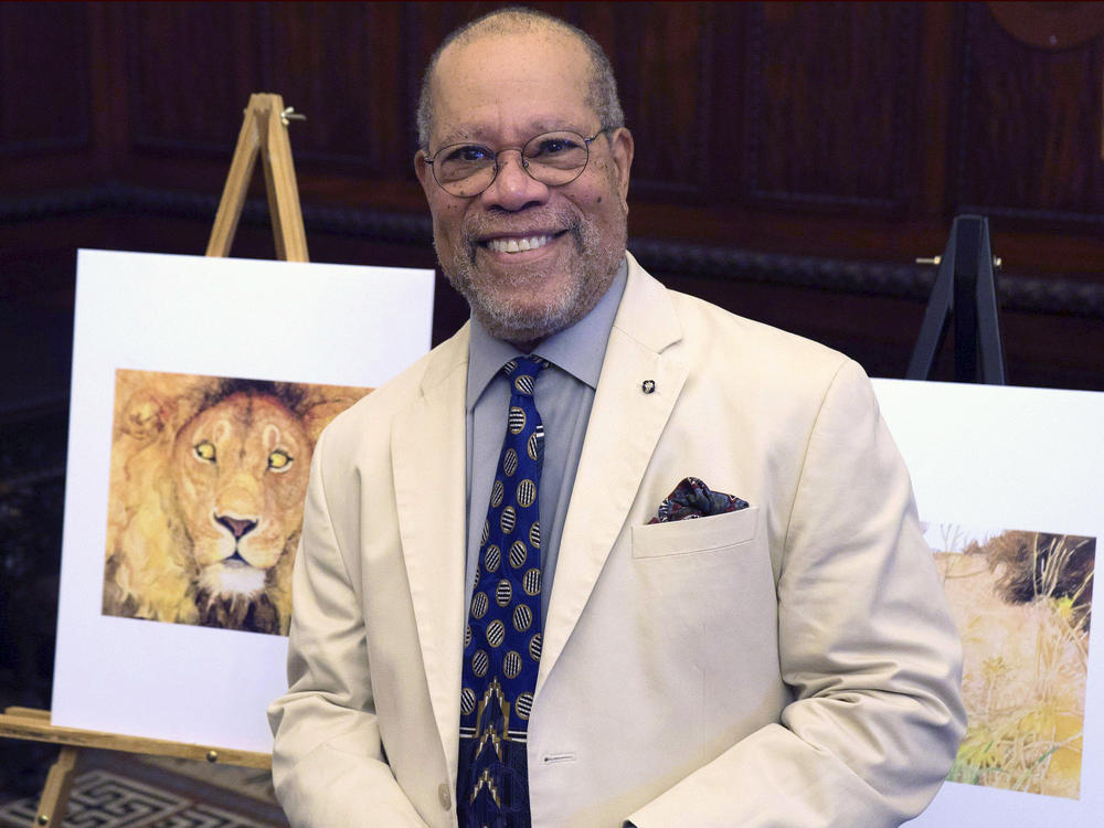 Children's book illustrator Jerry Pinkney poses in front of two of his illustrations in 2016, at the City Hall in Philadelphia.