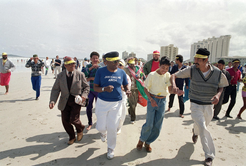 Desmond Tutu (center) jogs along a Whites-only beach with a crowd of supporters at the Strand in South Africa in 1989 as church organizations continued their campaign of defiance against apartheid laws.